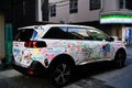 White SUV parked along the side of a street, featuring a vibrant display of colorful graffiti