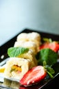 White sweet roll with kiwi, peaches, strawberries, mint. Serverd with almond peach and chocolate sauces on black plate Royalty Free Stock Photo