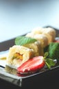 White sweet roll with kiwi, peaches, strawberries, mint. Serverd with almond peach and chocolate sauces on black plate Royalty Free Stock Photo