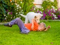 White Swiss Shepherd`s puppy and kid playing together on green g Royalty Free Stock Photo