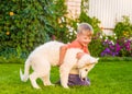 White Swiss Shepherd`s puppy and kid playing together on green g Royalty Free Stock Photo