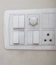 White switch board with on-off switches, fan speed regulator and three pin plug point installed in wall Royalty Free Stock Photo