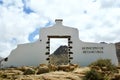 White symbolic wall with a doorway and a territory name sign in a dry landscape