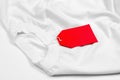White T-shirt on a white background with a red blank label. Blank red price tag on white t-shirt Royalty Free Stock Photo