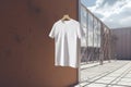 White T-shirt on a hanger on a background of wooden wall