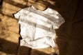 White t-shirt lies on burlap and shadow , fashion and trends