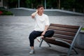 White T-shirt template on a guy sitting on a blurred background of a square on a bench looking into the distance clothes front