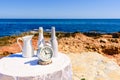 White table with antique clock placed on the rocks of the beach, with sea background Royalty Free Stock Photo