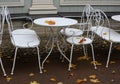 White table and chairs of the summer cafe are covered with yellow autumn leaves Royalty Free Stock Photo