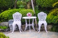 White table decorative with colorful flower in vase and two blank chair  in  outdoor garden view background Royalty Free Stock Photo