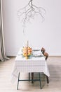 White table with dishes and food in the room. Yellow pumpkins on