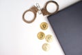 On a white table, the edge of a gray laptop, handcuffs, bitcoin coins and a globe. Near a copy space. Cybercrime concept