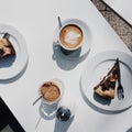 White table with great coffee latte and chocolate cake in the sun