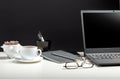 White table with laptop, coffee glasses for remote work or study. Black laptop with blank display layout template on black Royalty Free Stock Photo