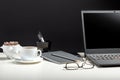 White table with laptop, coffee glasses for remote work or study. Black laptop with blank display layout template on black Royalty Free Stock Photo