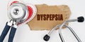 On a white table lie a heart, a stethoscope and a cardboard with the inscription - Dyspepsia