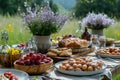 White table outdoors covered with various plates of food and bowls of fresh fruit in a field