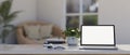 A white table with a white-screen laptop computer mockup in modern and comfortable living room Royalty Free Stock Photo