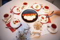 A white table is served for tea with carrot cake with strawberries and sour cream sauce