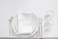 White table setting from above. Elegant empty plate, cutlery, napkin and glass