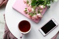 Cup of hot tea with mobile phone, flowers and book on white table Royalty Free Stock Photo
