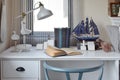 White table with wooden chair books and lamp in modern working area