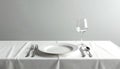 White tablecloth covers dining table with single setting. Clean empty plate, two forks, knife, spoon, clear wine glass wait for Royalty Free Stock Photo
