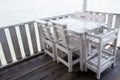 White tables and chairs in restaurant. empty rattan furniture coffee set table chair at wooden floor sea front by the sea. Royalty Free Stock Photo