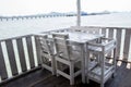 White tables and chairs in restaurant. empty rattan furniture coffee set table chair at wooden floor sea front by the sea. Royalty Free Stock Photo