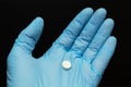 White tablet in a hand in a blue glove against a black background Royalty Free Stock Photo