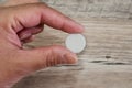 White tablet in hand on a wooden background, close-up. Health concept. Royalty Free Stock Photo