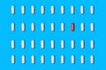 White tablets are arranged in rows, one of them is red on a blue background Royalty Free Stock Photo