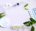 White tablets, glass ampoules, a syringe and cherry blossoms are arranged on a white background. Spring allergy