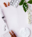 White tablets, glass ampoules, a syringe and cherry flowers are arranged on a white background.