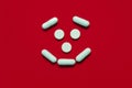 White pills round and oblong in the form of a kind smile on a red background, medical concept Royalty Free Stock Photo