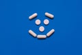 White tablets of rounded and oblong shape in the form of a good smile on a blue background, medical concept Royalty Free Stock Photo