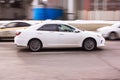 White Taxi car on the street in motion. Side view of Toyota Camry rides on city road with motion blur. Fast way to drive through Royalty Free Stock Photo