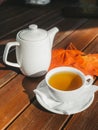 White tea cup with black tea, white teapot on wooden table and autumn maple leaves Royalty Free Stock Photo