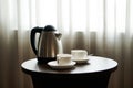 White tea cup coffee cup on the table by a sofa couch in hotel room, kettle Royalty Free Stock Photo