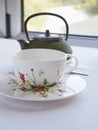 white tea cup decorated with painted flowers and oriental teapot