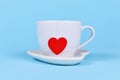 White tea cup with red heart shaped tea bag paper on blue background Royalty Free Stock Photo