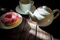 White tea cup, white teapot and donut on a white saucer on a wooden table Royalty Free Stock Photo