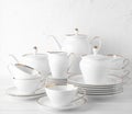 White tea set on a white background. Teapot, cream, sugar bowl, cups, saucers, plates on the table. Royalty Free Stock Photo