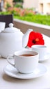 White teacup and teapot on table with flower in soft focus, outdoor setting. Royalty Free Stock Photo