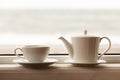 White teacup and teapot on the windowsill. Soft focus. Royalty Free Stock Photo