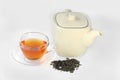 White teapot, a cup of tea and dried tea leaves. Royalty Free Stock Photo