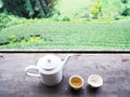 White teapot and cups on vintage wooden table over green tea farm background Royalty Free Stock Photo