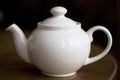White teapot on a dark wood table
