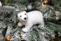 white teddy bear sitting on Christmas tree in snow, Christmas tree decor, festive concept, lights Royalty Free Stock Photo
