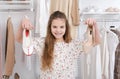 Teenage girl 10 years old holds shoes in her hands against the background of a wardrobe with clothes in light beige tones Royalty Free Stock Photo